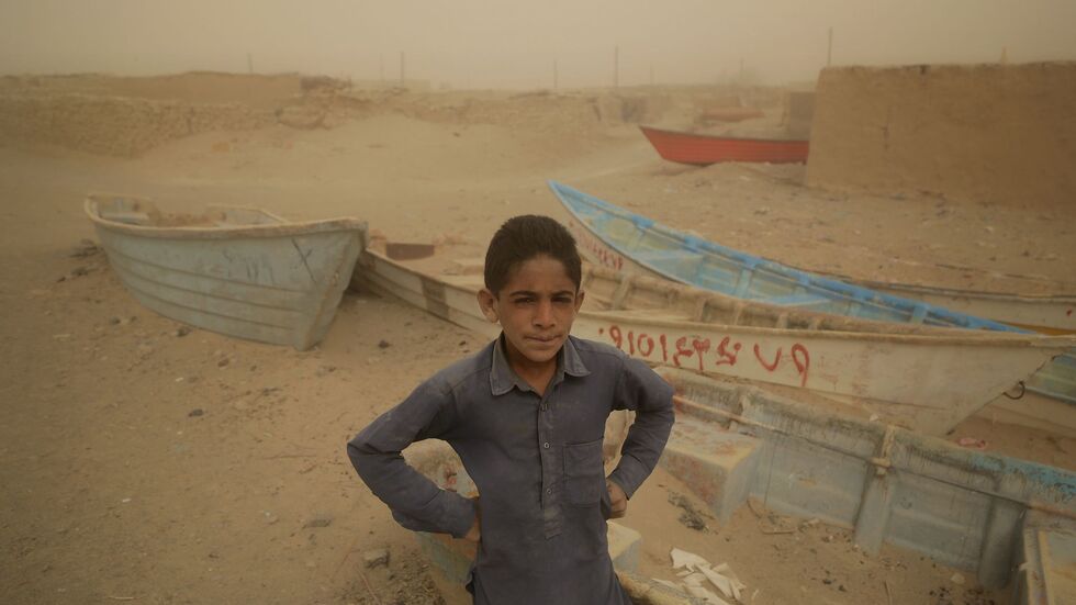 Ein Junge im Iran steht vor alten Booten, wo einst ein See war.