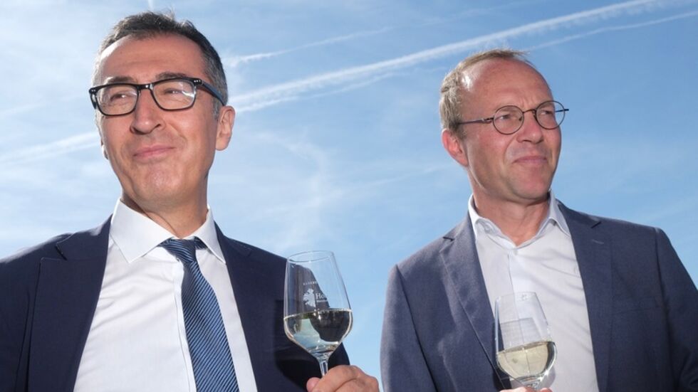 Cem Özdemir (Grüne/ l), Bundeslandwirtschaftsminister, und Wolfram Günther (Grüne), Landwirtschaftsminister des Landes Sachsen, stehen mit Weingläsern beisammen. Sie besuchten zusammen die Weinberge an der Elbe.